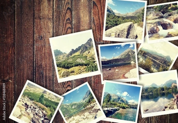 Fototapeta Heap of the vintage photos from holiday in mountains with traditional white frame placed on wooden desk.