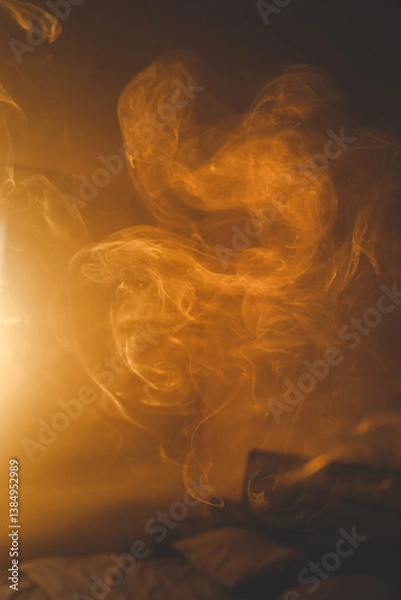 Fototapeta Soft swirling smoke in warm golden light above a bed, creating a dreamy and abstract mood with smooth flow and ethereal atmosphere