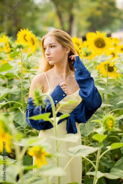 Obraz Cute european young model girl posing and having fun in a field full of blooming sun flowers. Showing freedom, innocence and youth