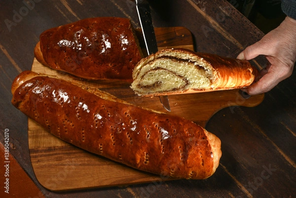 Obraz Freshly baked bread being sliced on a wooden board in a cozy kitchen setting during the afternoon