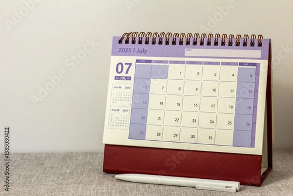 Fototapeta A desktop calendar for July 2025 on a desk with space to copy.