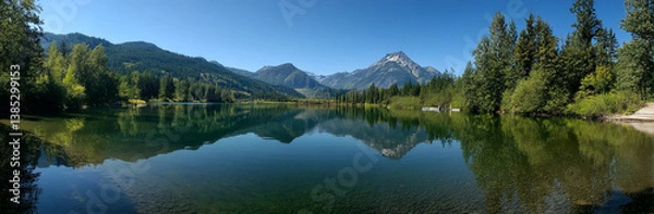 Fototapeta Panoramic photo of Lake. The lake is clear and calm, reflecting the surrounding mountains and trees in its surface. In front of it stands Mount Hood with snow-capped peaks against a blue sky backgroun