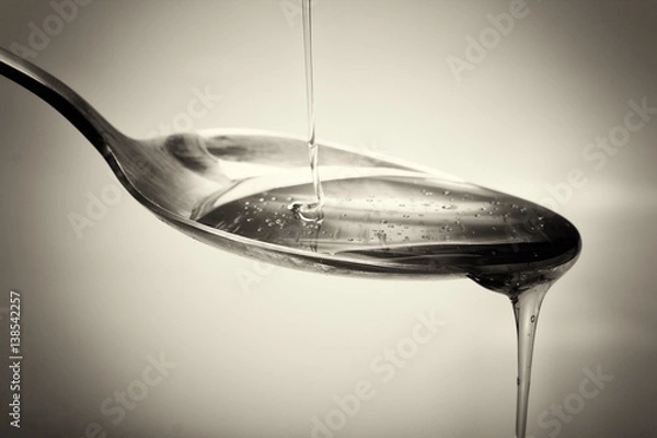 Obraz Honey pouring from spoon against a light background