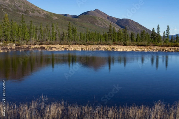 Fototapeta Reflection of mountains in calm water of the lake. Lake Labynkyr. Yakutia. Russia.