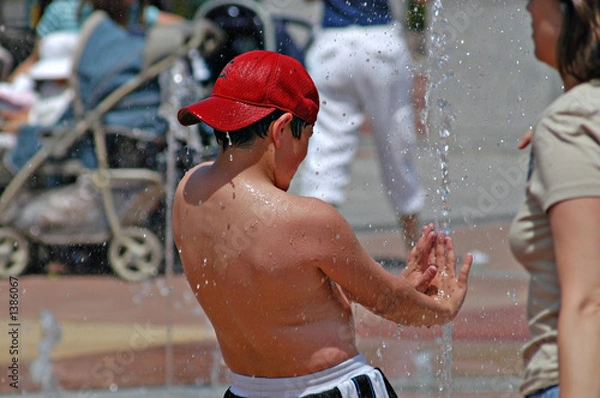 Fototapeta boy playing in fountain getting sprayed by water