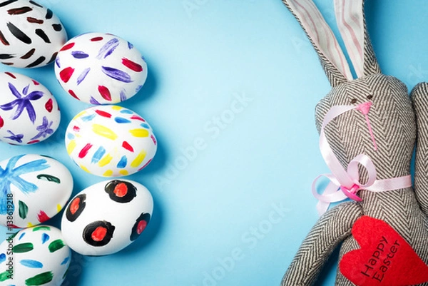 Fototapeta Easter bunny on a blue background. Rabbit. Easter ideas. Easter eggs. Space for text. Black lettering on a heart happy easter.