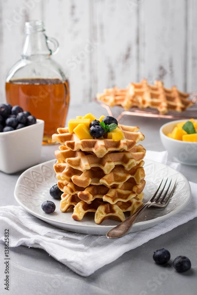 Fototapeta Stack of delicious homemade waffles with fresh fruit and berries on light background