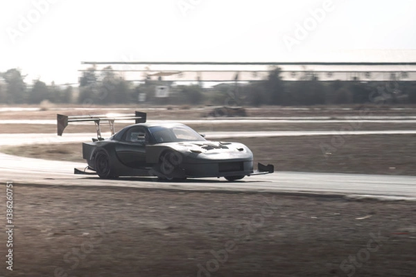 Fototapeta Gray-tuned sports car drifting on a racetrack during an intense time attack competition, showcasing speed and precision in every turn