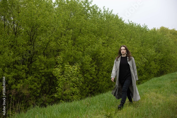 Fototapeta young woman in coat in spring greenery, trees and grass in nature