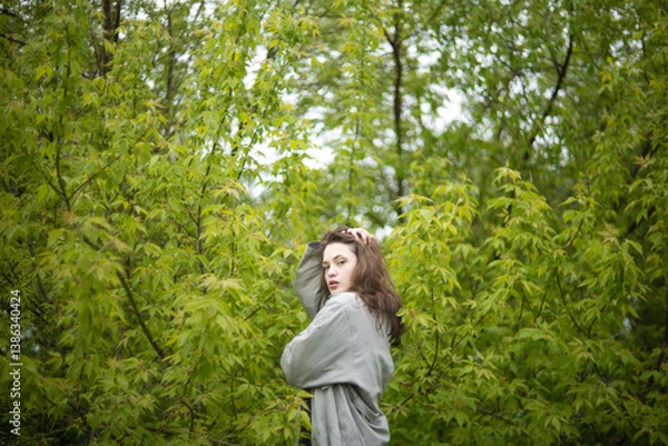 Fototapeta young woman in coat in spring greenery, trees and grass in nature