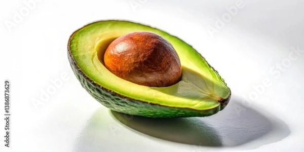Fototapeta Eine reife Avocado mit halber Schale auf einer wei?en Oberfl?che isoliert, im Licht der Sonne gelegt
