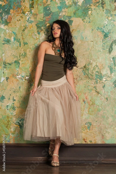 Fototapeta Cute young fashion woman standing against green stucco wall background