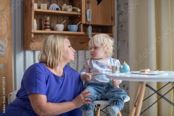 Fototapeta Grandmother with grandson boy at home. Relatives bonding and generational communication. Old lady and child having fun together.