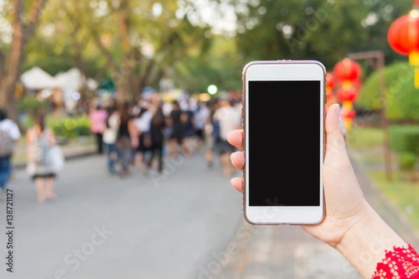 Fototapeta Hand holding Smartphone with blurred street background