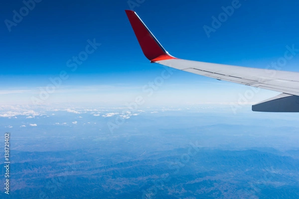 Fototapeta Wing of an airplane flying above the clouds