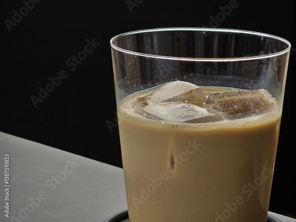 Obraz Creamy iced coffee with ice cubes in glass, set against dark background, evokes refreshing and indulgent feeling