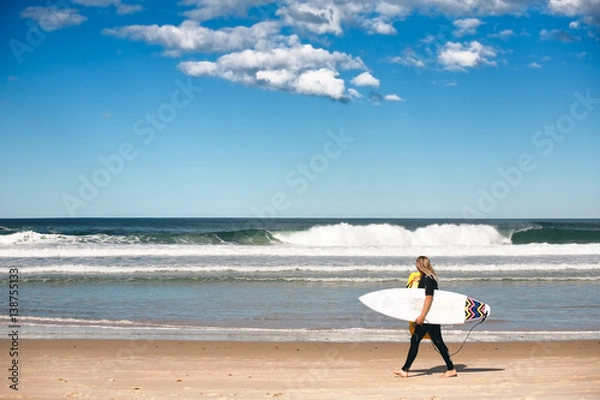 Obraz surfer walk along the shore of byron bay beach, NSW Australia.