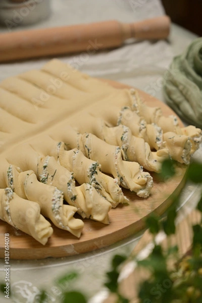 Obraz Close up twisted dough strips on wooden board. Green towel, rolling pin, microgreens on kitchen table. Home cooking baking puffs