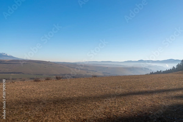 Fototapeta In the distance, the snow-capped mountains rise up – the majestic Tatra Mountains in Slovakia. Their snow-white peaks contrast effectively with the sky, creating an atmosphere of tranquility and natur
