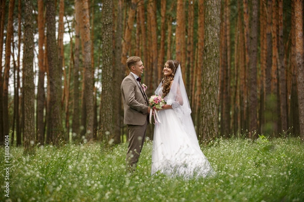 Fototapeta Bride and groom holding hand and looking at each other in forest. Rustic wedding
