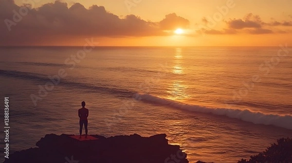 Fototapeta A person practicing yoga at sunrise by the ocean with calm waves representing a fresh start