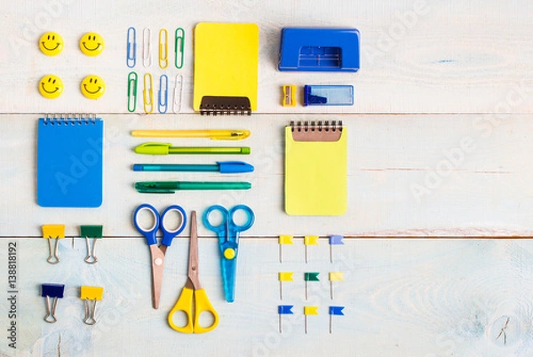 Obraz School stationery products such as paper clips, pins, notebooks, pens, pencils, rulers, scissors lying on blue wooden table with space to write your ad text