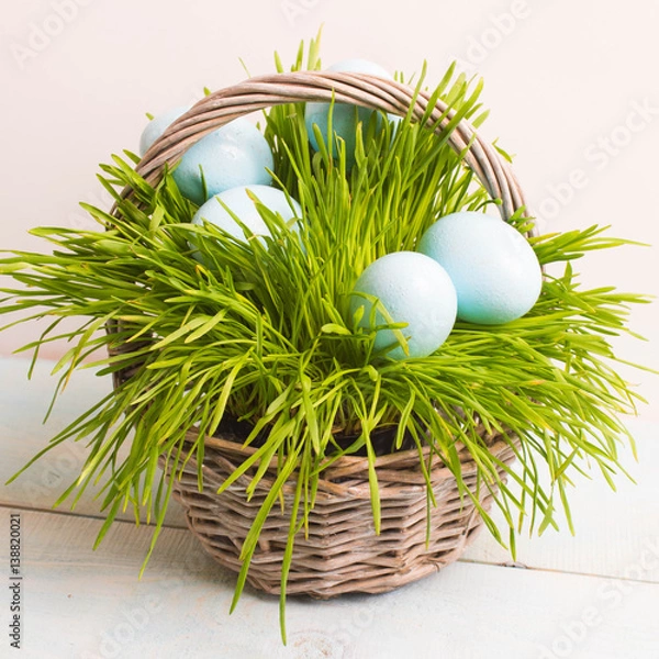 Obraz Blue Easter eggs in basket, grass on wooden background