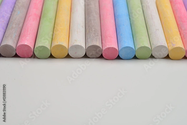 Obraz Pieces of chalks in a variety of colors arranged in line on a white background. Back to school,education, arts, creative. Image with room for text