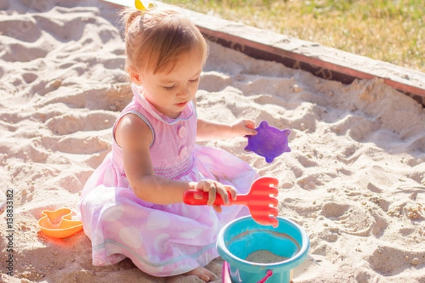 Obraz Little girl playing with sand in a sandbox
