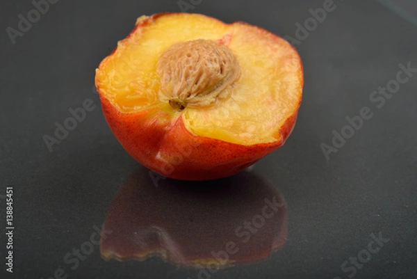 Obraz Close up image of a peach cut in half on black background. Section through the middle of the fruit, kernel. Selective focus