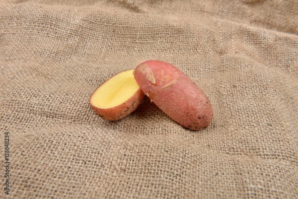 Obraz New fresh red potatoes cute in two on jute background. Concept of healthy food, bio from countryside