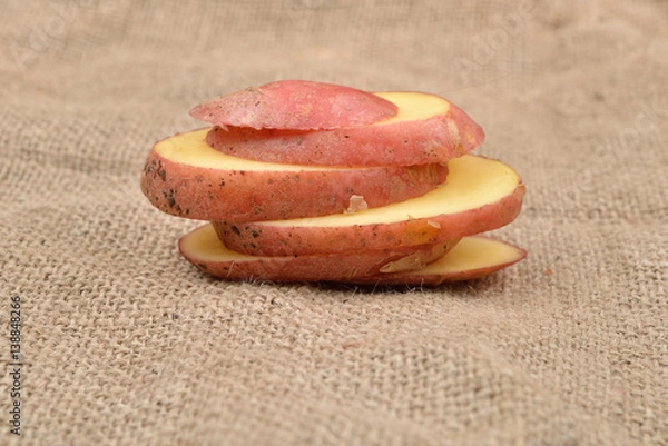 Obraz New fresh red potatoes cute in slices on jute background. Concept of healthy food, bio from countryside