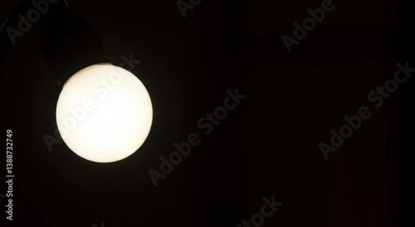 Fototapeta Illuminated Orb in the Dark: A Glowing Lightbulb Against Pitch Black Background