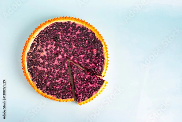 Fototapeta Large blueberry pie with a cut-off piece in close-up on a light background, kopi space