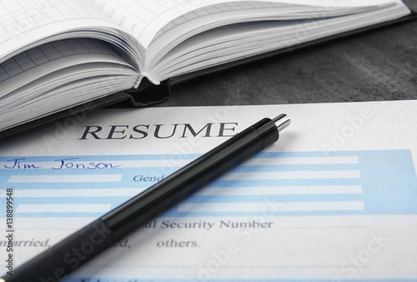 Fototapeta Resume with pen and notebook on table, closeup