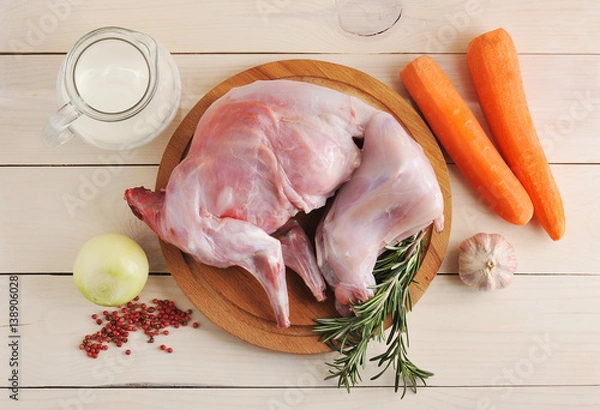 Fototapeta raw rabbit on a wooden Board with ingredients for stewing milk, onion, carrot, rosemary