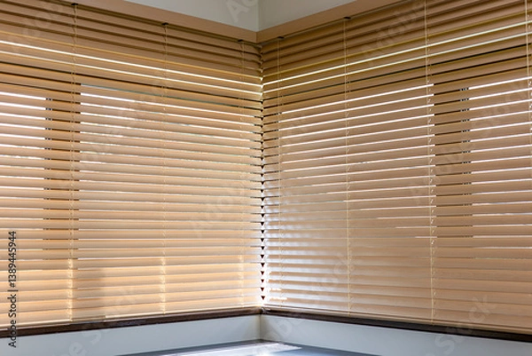 Obraz Corner view of beige wooden blinds meeting at a right angle. Light softly filters through the slats of motorized wood blinds, casting shadows onto the window sill and enhancing the cozy interior.