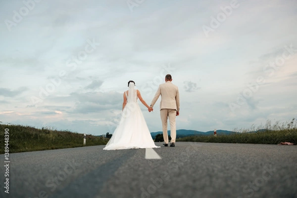 Fototapeta Together on the road ahead, hand in hand. Standing still for a moment, yet moving toward forever — their journey begins on this path, paved with love and endless promise