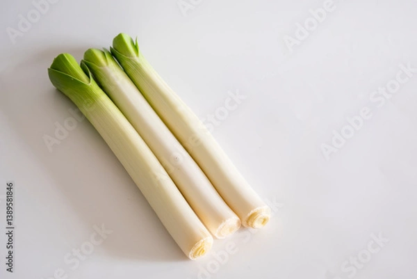 Fototapeta Three stalks of fresh green leek isolated on a white background with copy space. Allium ampeloprasum var. porrum, or spring onion, is one of the varieties of the Allium ampeloprasum species.