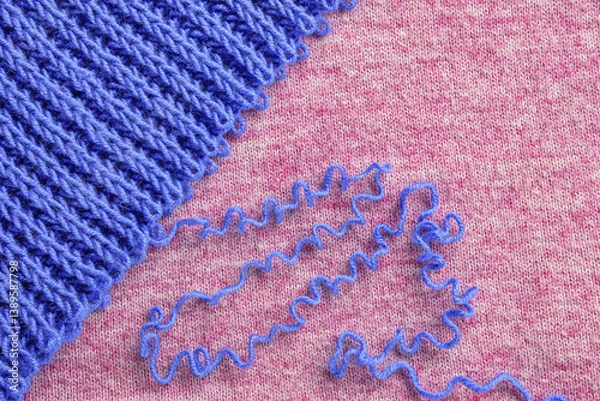 Fototapeta Unravelling blue wool knitted garment on pink background. Copy space