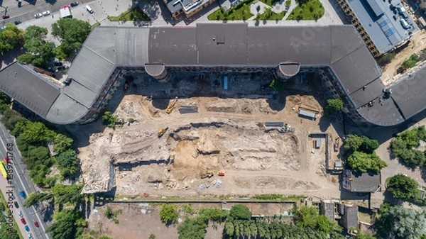 Fototapeta Drone aerial top view to the land plot on which the construction process is taking place on a sunny summer day. Building former factory Arsenal. Kyiv Kiev capital of Ukraine