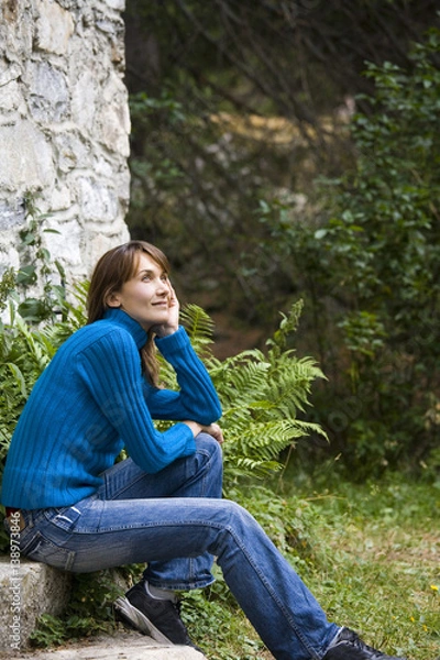 Fototapeta femme paisible assise devant un chalet dans l'herbe