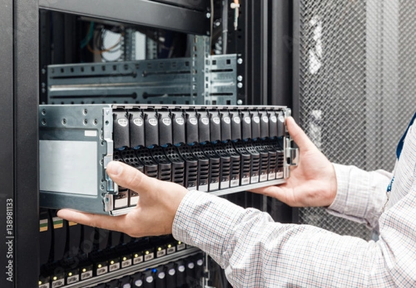 Fototapeta IT Engineer installs enclosure with hard disk drive in the storage system