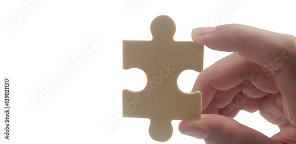 Fototapeta Hand holding puzzle piece close-up conceptual image minimalist background focus on problem solving