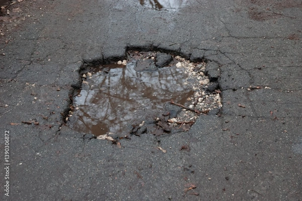 Fototapeta a puddle in a deep hole in an asphalt road