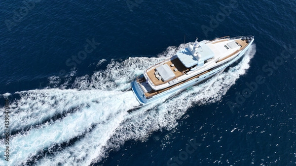 Obraz Aerial drone tracking photo of beautiful modern super yacht with wooden deck cruising in low speed deep blue Mediterranean sea
