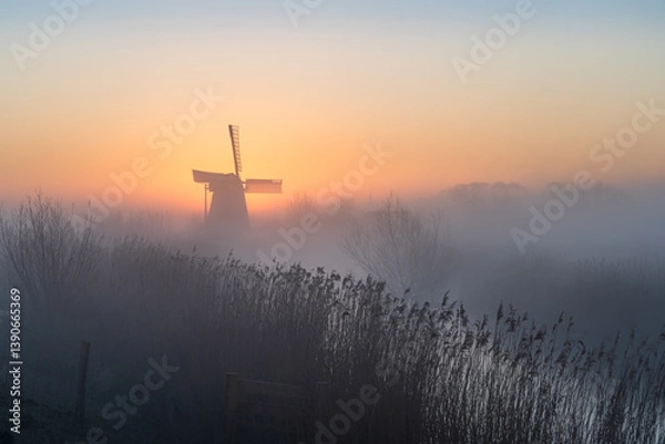 Fototapeta Dawn at a traditional, Dutch windmill in the spring fog.