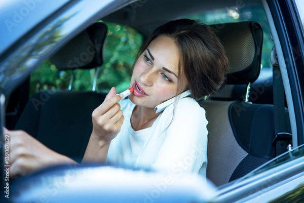 Obraz busy girl with lipstick and phone while driving
