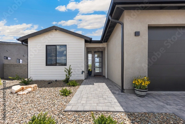 Obraz A charming small white house that features a black garage door