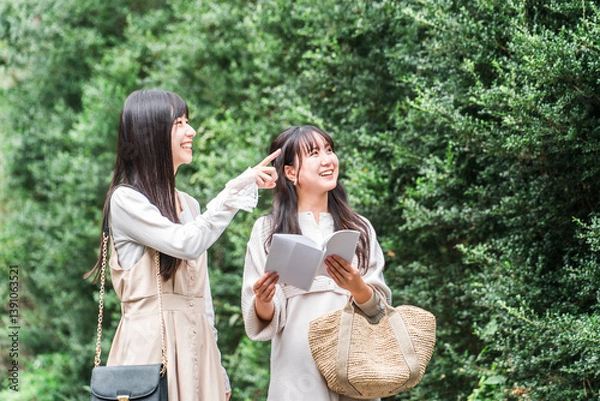 Fototapeta ガイドブックを見ながら観光地を歩く若いアジア人女性（女子旅・トラベル・観光）
